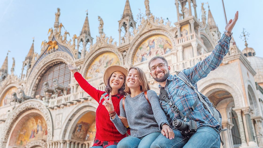 Friends enjoying San Marco Square, Venice, with St. Mark's Basilica in the background.