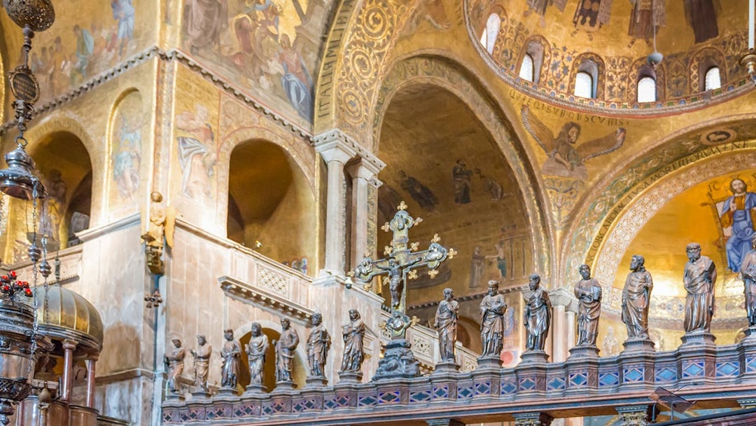 Interior of St. Mark's Basilica in Venice with ornate golden mosaics and statues.