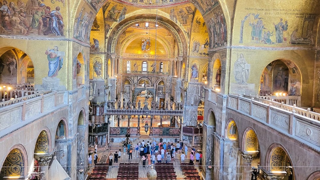 Interior view of St. Mark's Basilica with visitors and ornate mosaics, Venice, Italy.