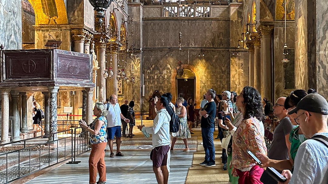 Visitors inside St. Mark's Basilica, Venice, using audioguides to explore the ornate interior.