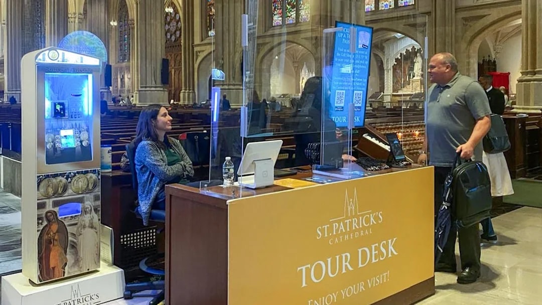 Tour desk inside St. Patrick's Cathedral with visitor and staff interaction.