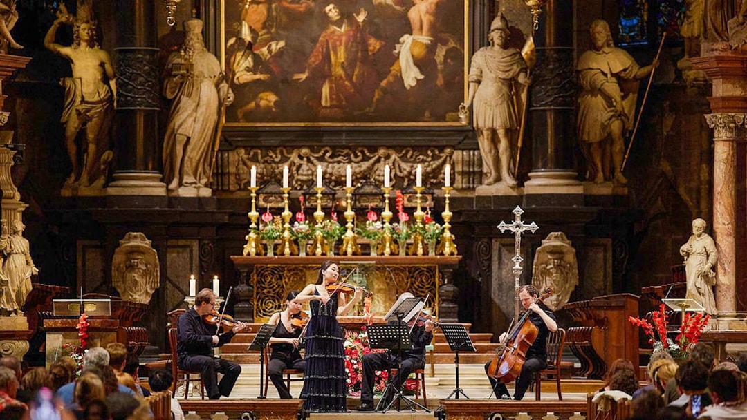 Orchestra performing inside St. Stephen's Cathedral, Vienna, with audience watching.
