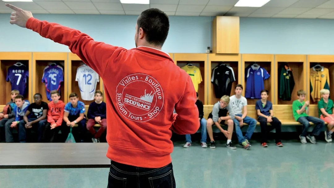 Guide leading a tour group in the Stade de France locker room, Paris.