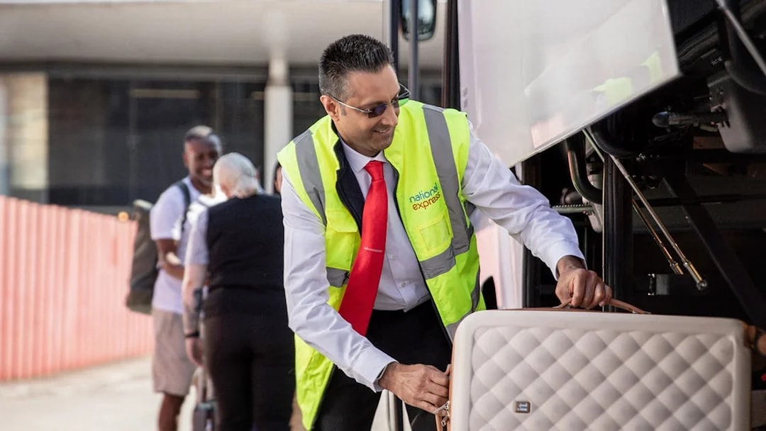 Bus staff loading luggage for Stansted Airport to London Victoria route.