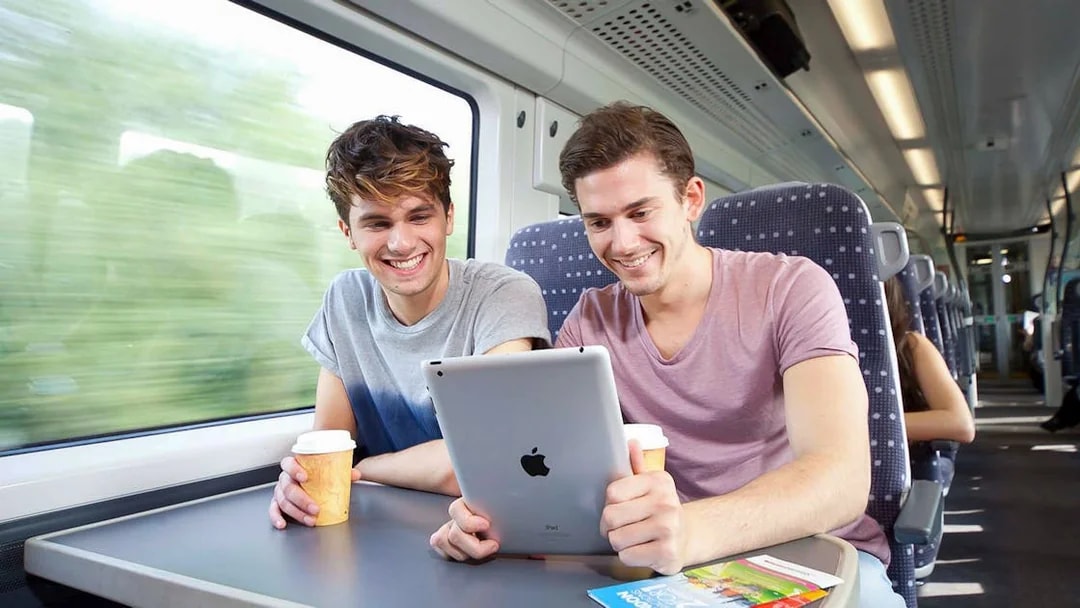 Passengers enjoying a tablet and coffee on the Stansted Express train to Stratford.