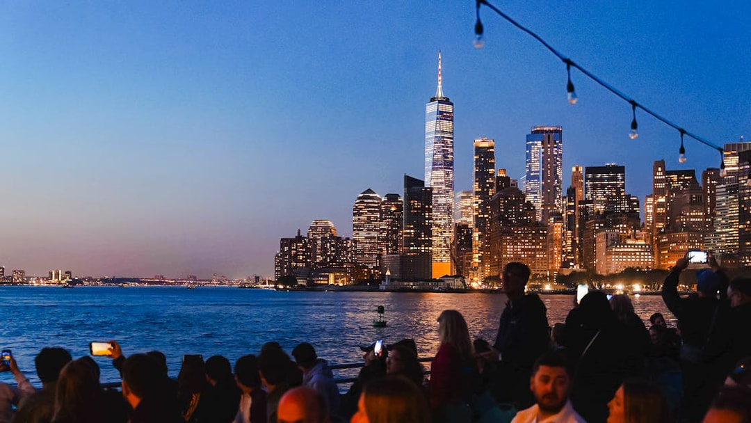 New York City skyline at night with people on a boat tour.