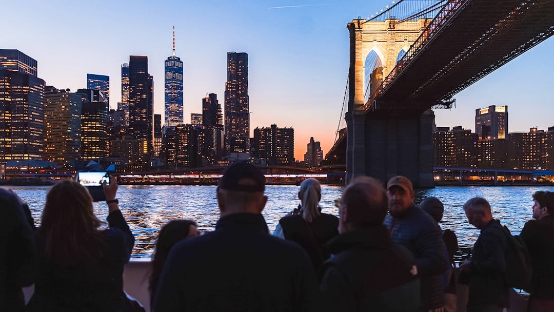 Brooklyn Bridge illuminated at night with New York City skyline in the background.