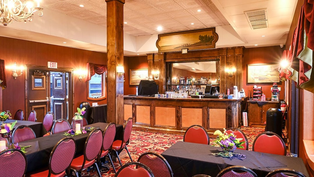Dining area with tables and chairs, warm lighting, and a bar in Steamboat Natchez.