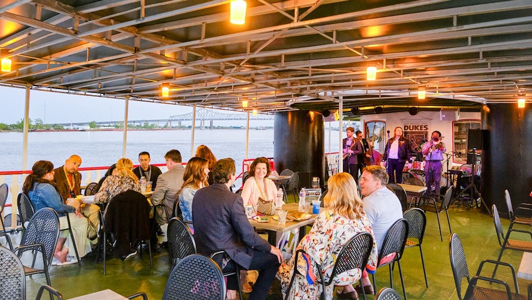 People dining on Steamboat Natchez with live band and river view in New Orleans.