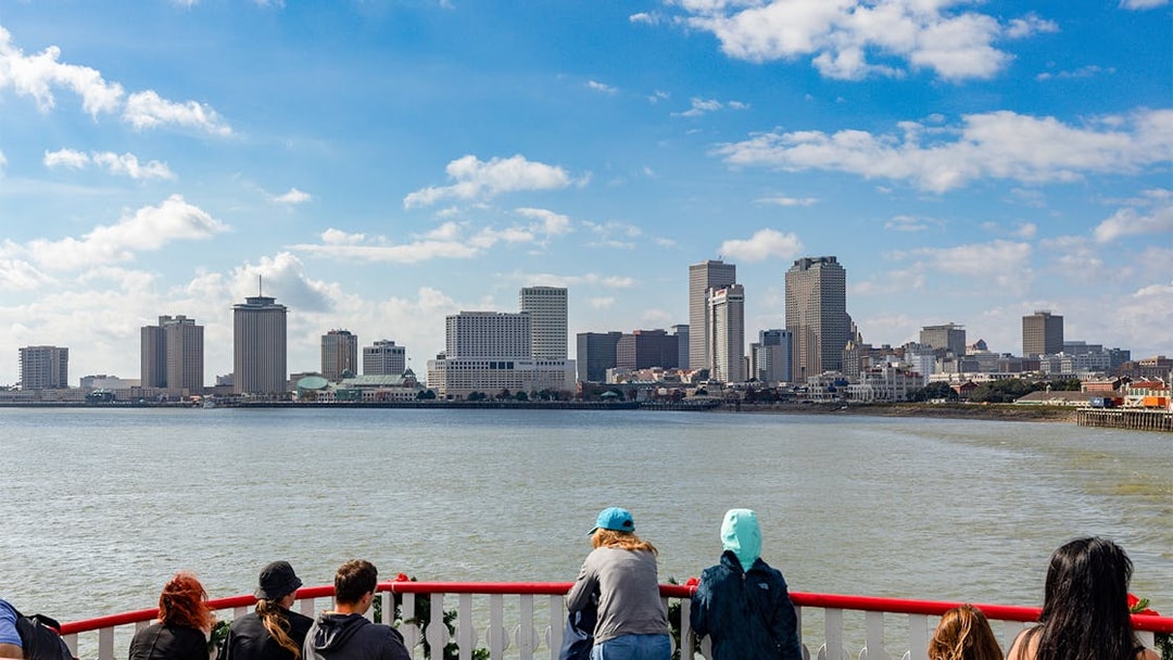 Tourists on Steamboat Natchez deck view New Orleans skyline.