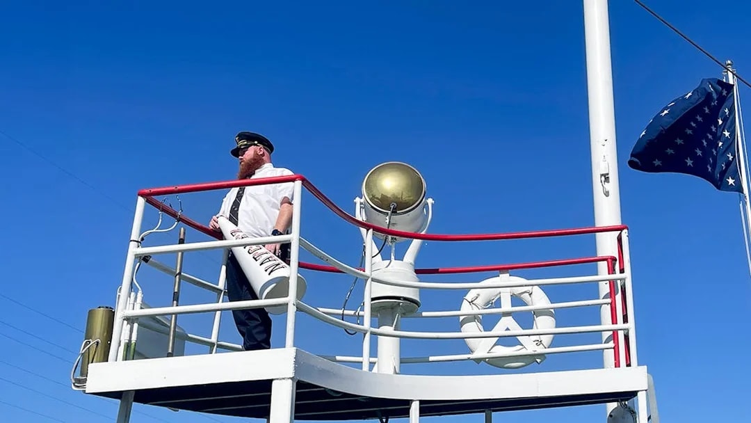 Captain on deck of the Steamboat Natchez with megaphone and flag.