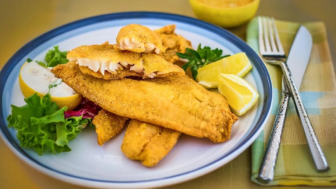 Breaded catfish with lemon wedges on Steamboat Natchez lunch cruise plate.