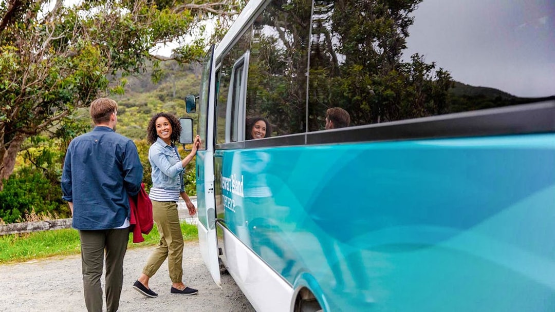 Tourists boarding a bus for the Stewart Island Village and Bays Tour.