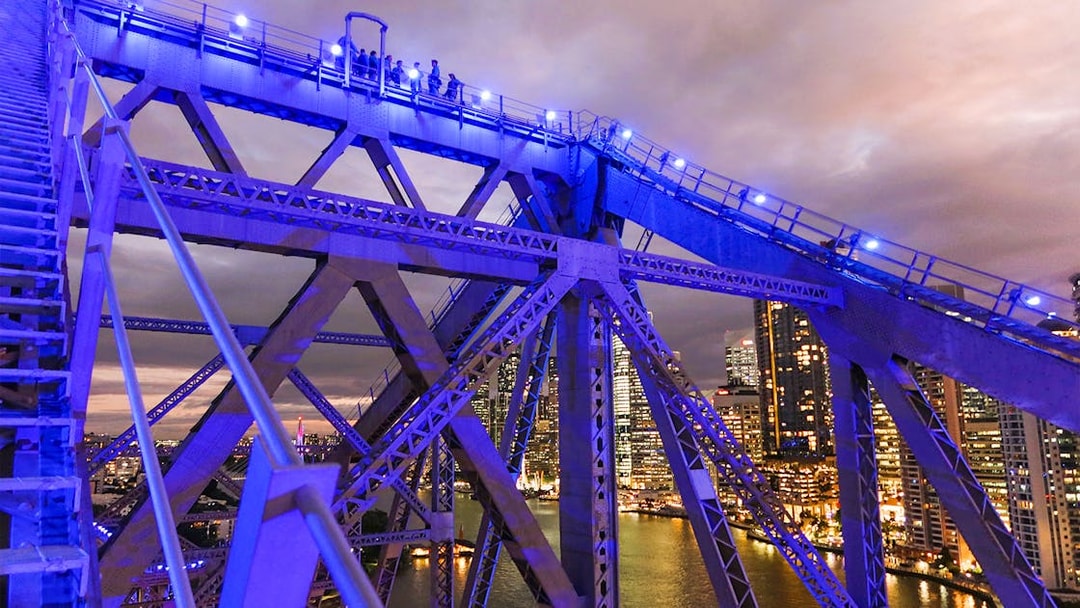 Climbers on Story Bridge at night with city skyline in Brisbane.