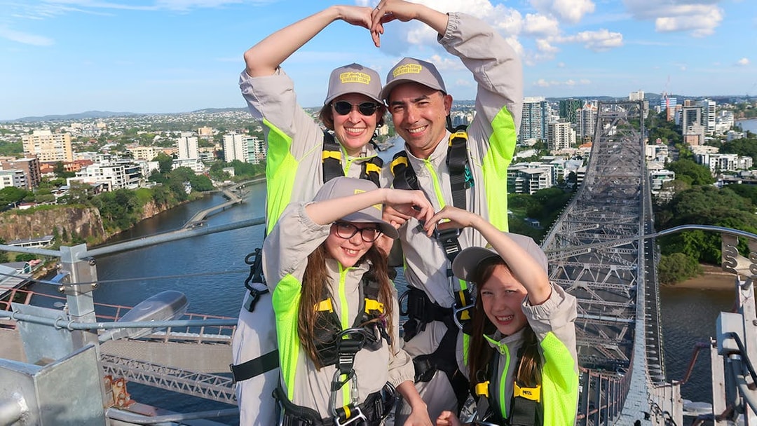 Family making heart shape with arms atop Story Bridge, Brisbane.