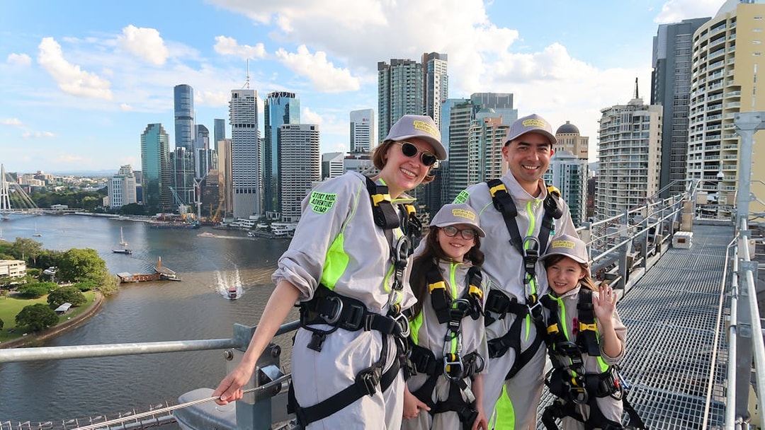 Family in harnesses on Story Bridge Adventure Climb, Brisbane skyline in background.