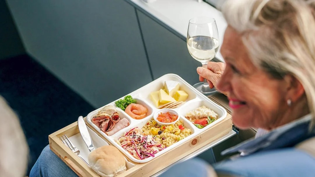 Salmon and assorted lunch on a cruise with a person holding a glass of wine.
