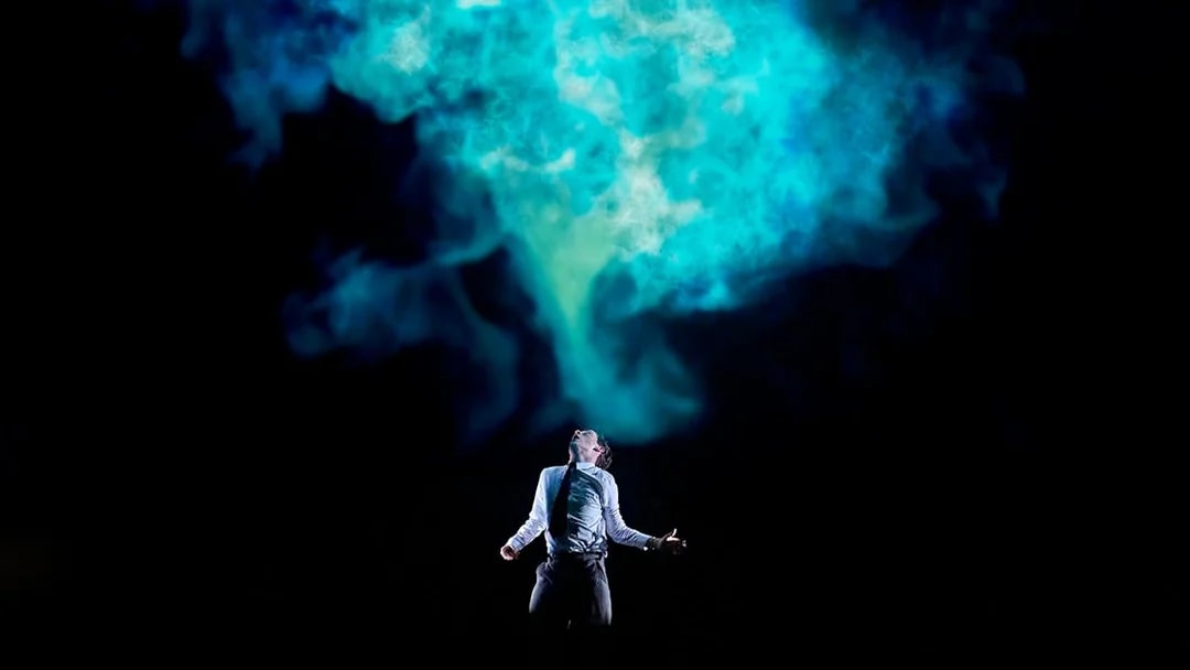 Person standing under blue smoke in a dramatic scene from Stranger Things: The First Shadow.