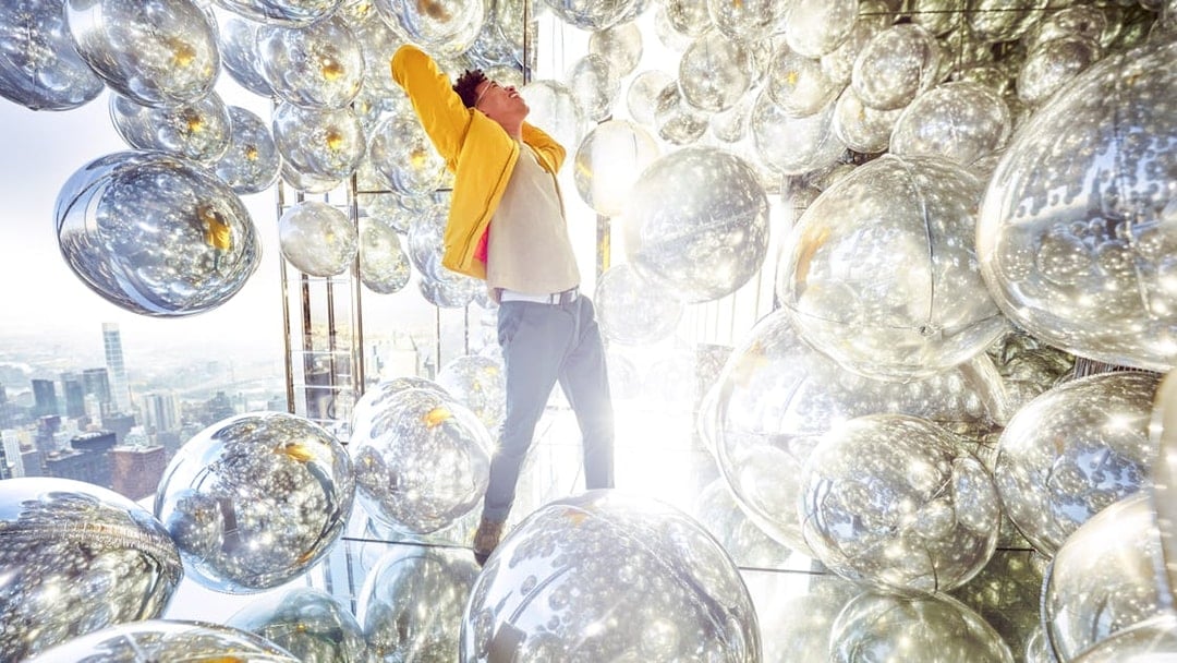Person inside Air exhibit at SUMMIT One Vanderbilt, surrounded by reflective spheres, New York City.