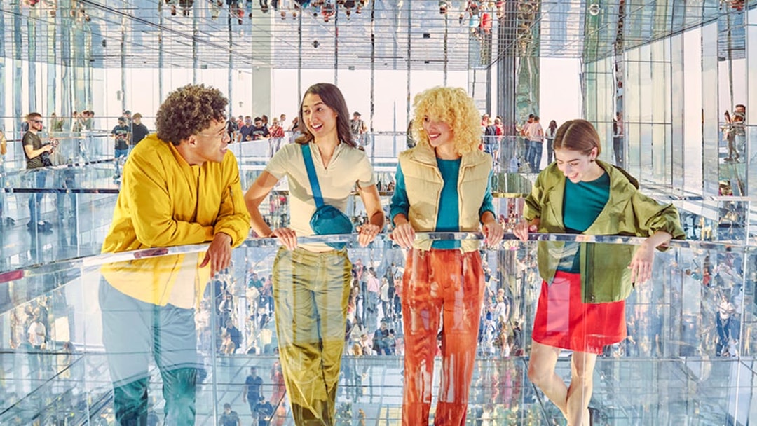 Four people standing on mirrored floor at SUMMIT One Vanderbilt, New York City.