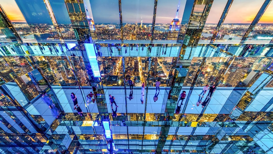 Interior view of SUMMIT One Vanderbilt with mirrored reflections and New York City skyline.