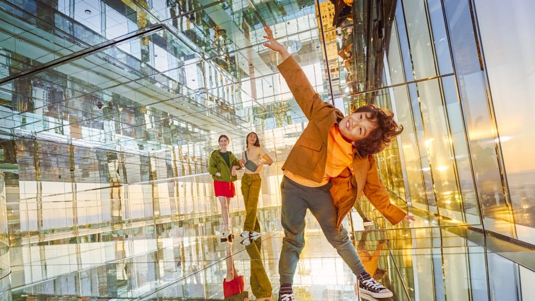 Three people enjoying the mirrored interior of SUMMIT One Vanderbilt observation deck, New York City.