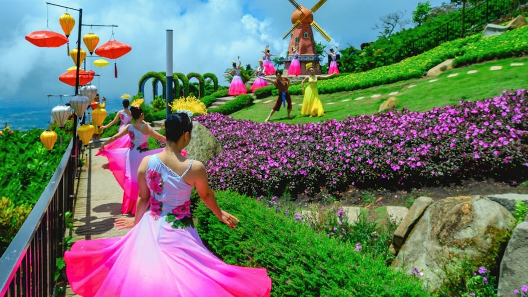 Dancers in colorful dresses perform near a windmill at Sun World Ba Den Mountain.
