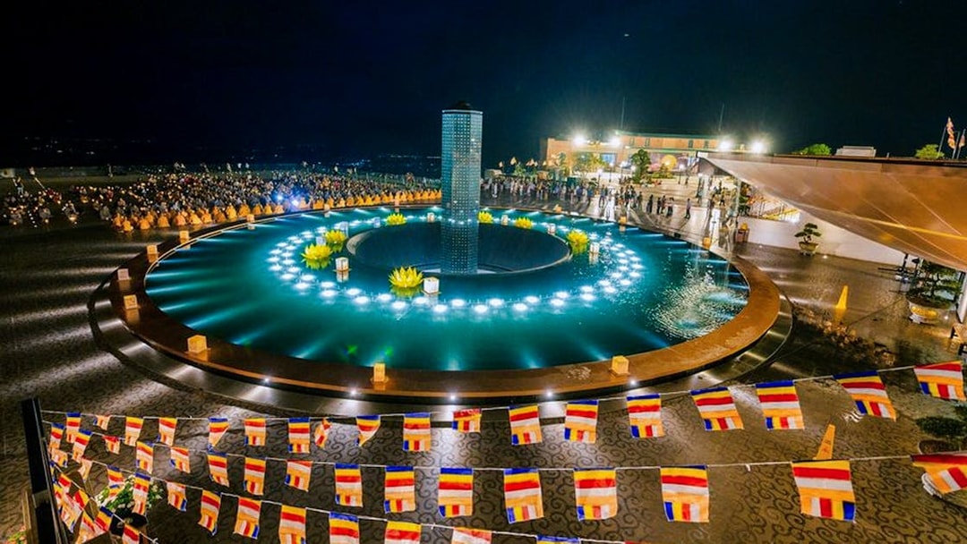 Colorful flags and illuminated fountain at night, Sun World Ba Den Mountain, Vietnam.