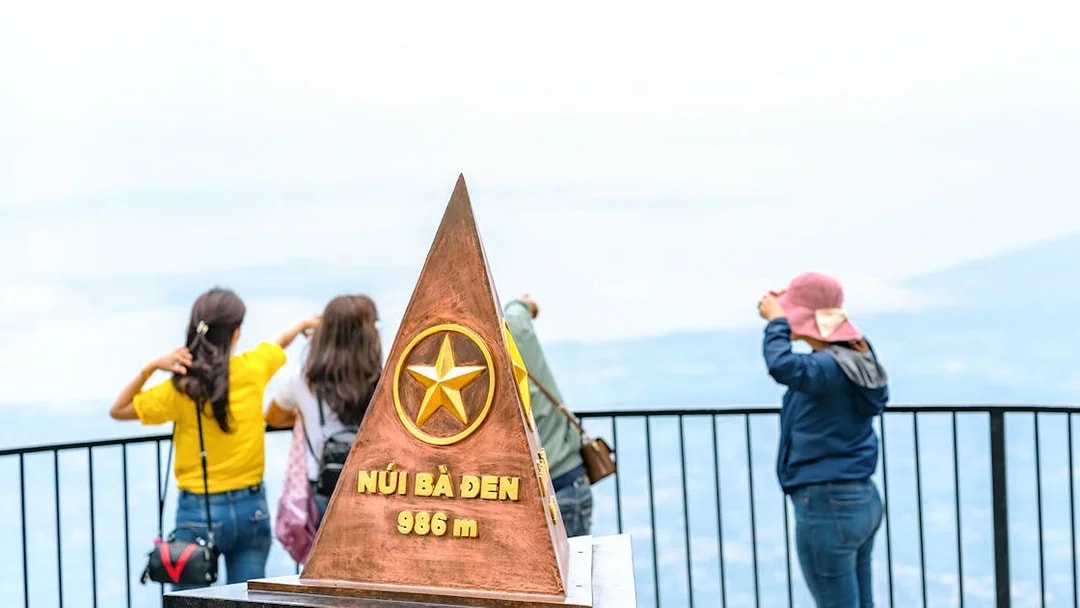 Ba Den mountain summit marker with tourists enjoying the view.