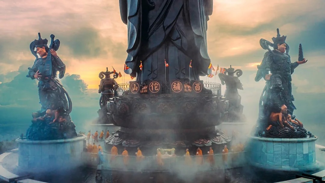 Statues and monks at Hang Pagoda on Ba Den Mountain, Vietnam, during sunrise.