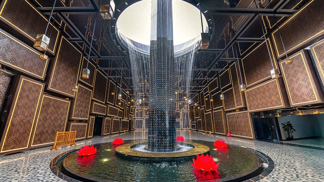 Water feature with red lotus flowers inside Ba Den Mountain tourist area, Tay Ninh, Vietnam.