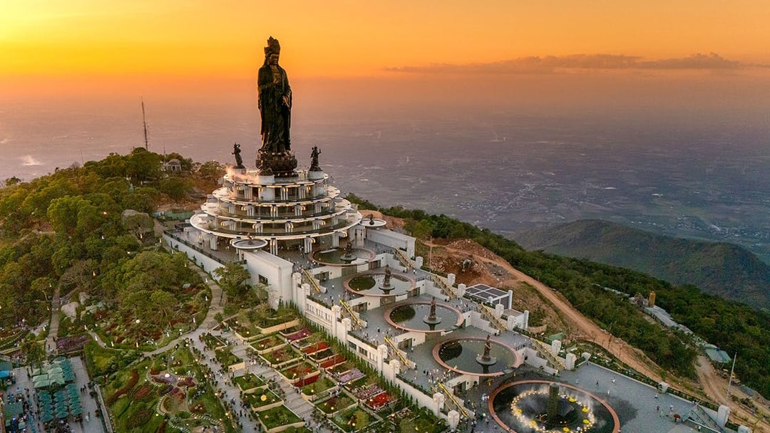 Guanyin statue in Tay Ninh province at sunset with surrounding gardens and visitors.