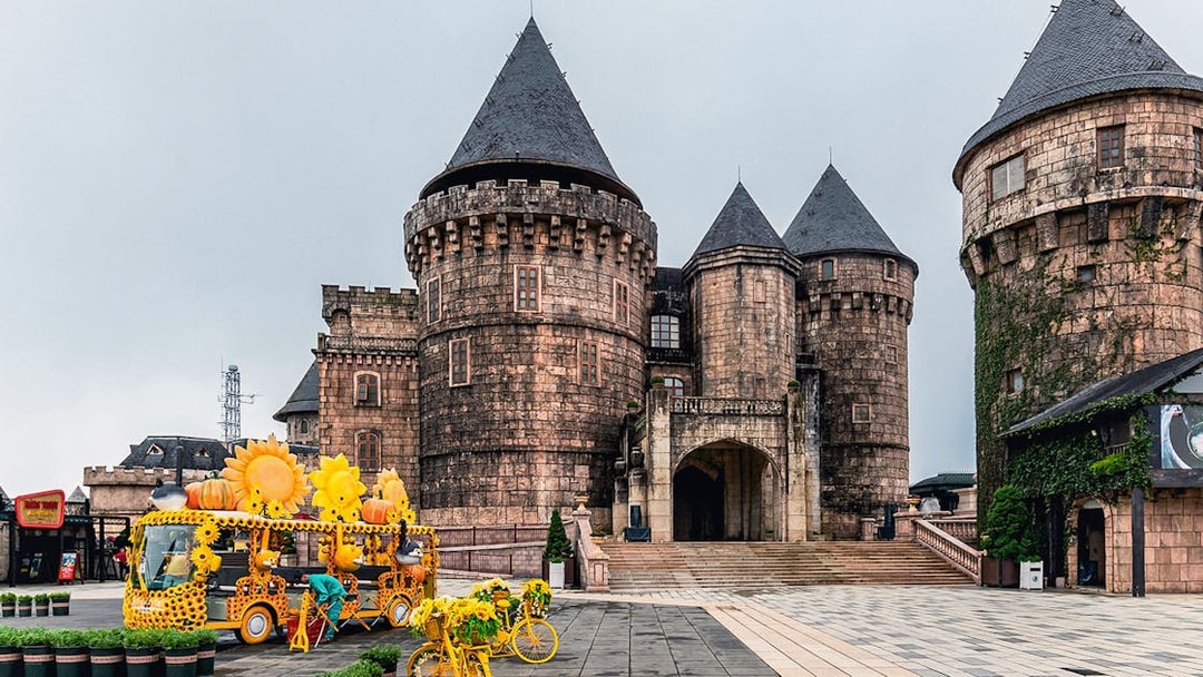 Central square in Ba Na Hills with castle towers and sunflower-themed decorations.