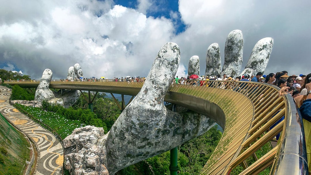 People walking on the Golden Bridge held by giant hands in Ba Na Hills, Vietnam.