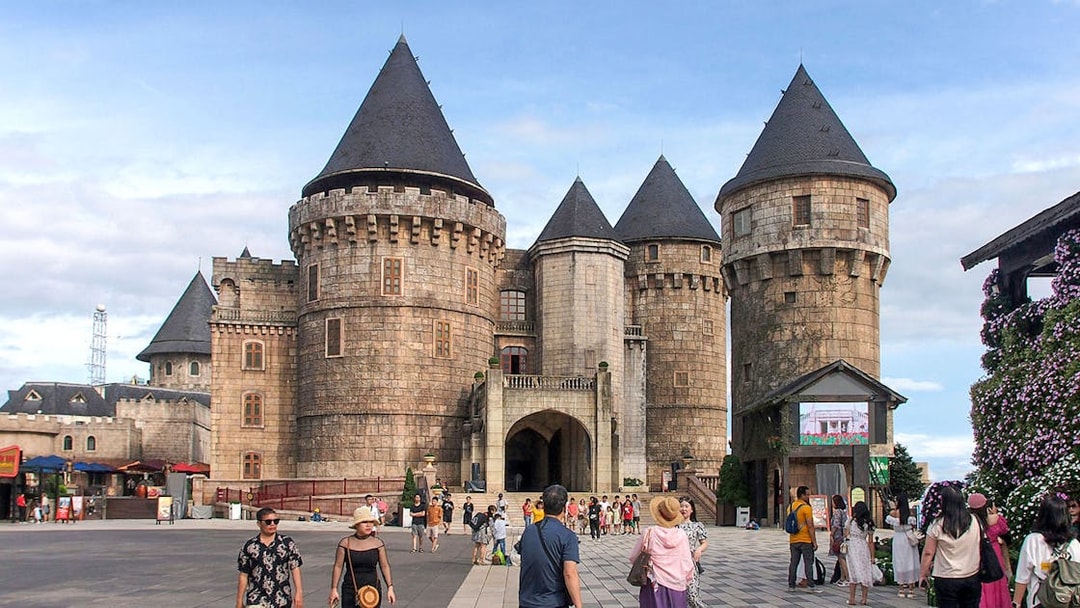 Stone castle towers at Ba Na Hills with tourists exploring the courtyard.