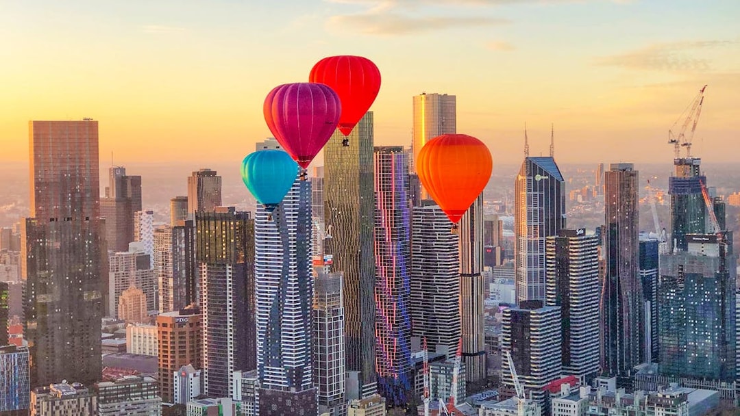 Hot air balloons over Melbourne skyline at sunrise.