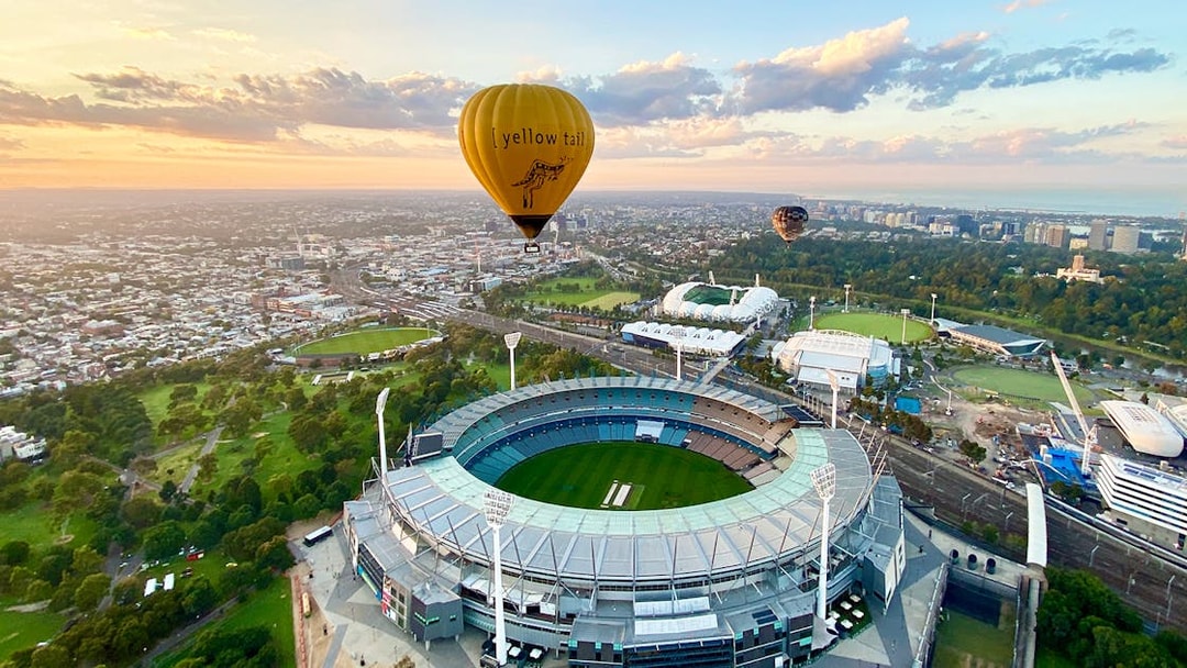 Hot air balloon over Melbourne Cricket Ground at sunrise.