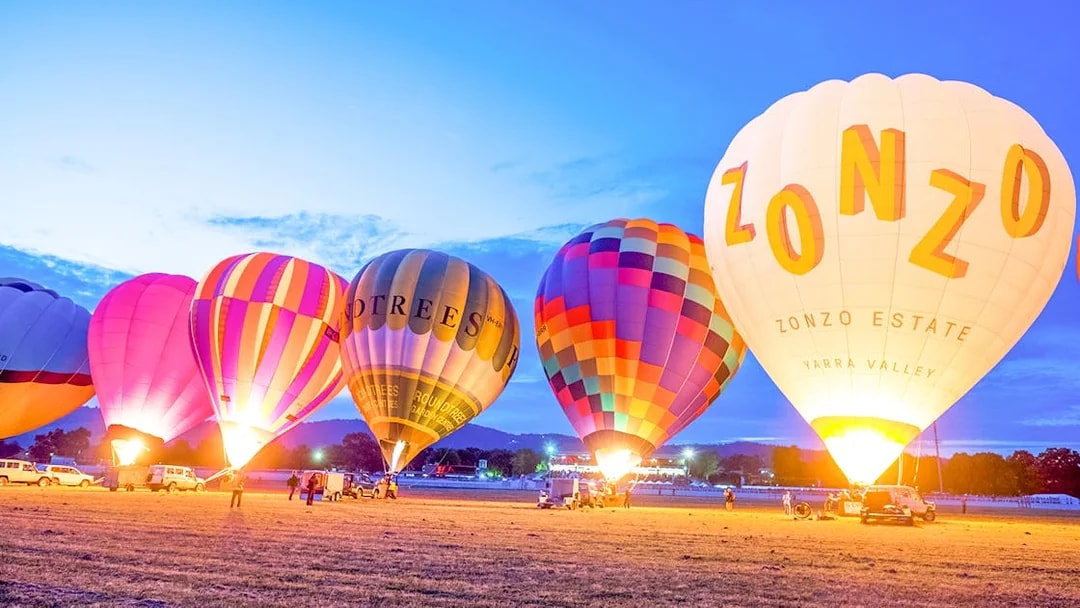 Hot air balloons preparing for sunrise flight over Melbourne field.