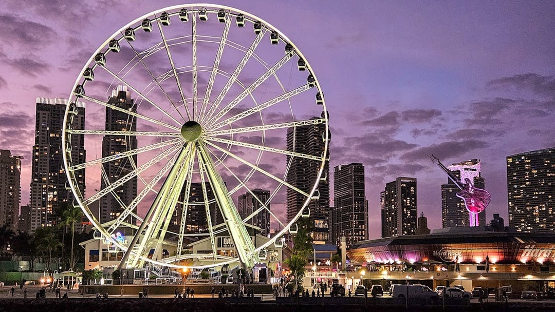 Miami skyline with Ferris wheel and cityscape at dusk, viewed from a luxury yacht cruise.