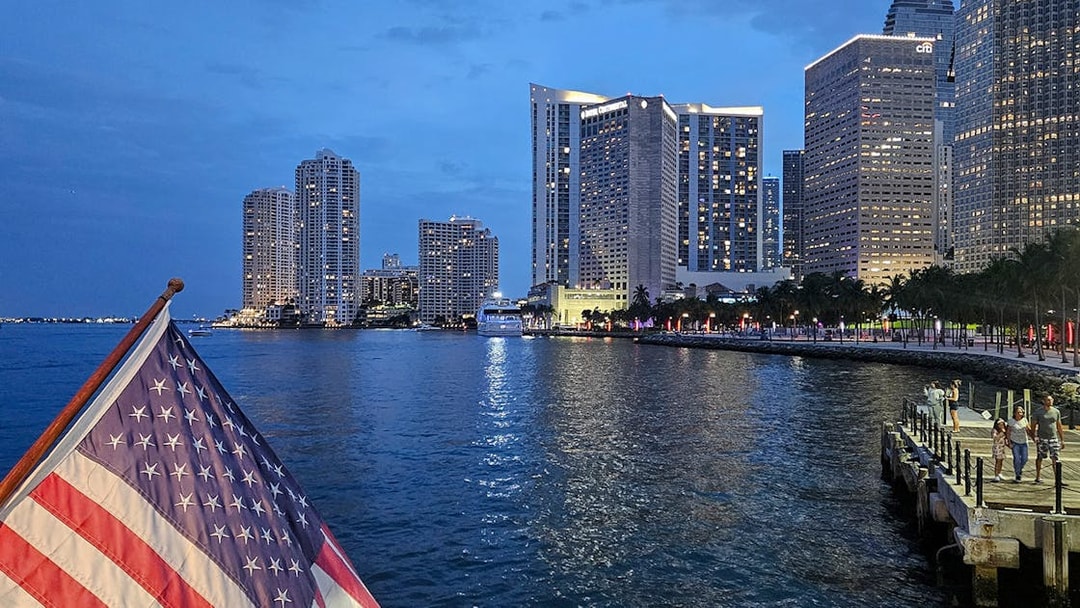 Sunset view of Biscayne Bay with Miami skyline and American flag on a cruise.