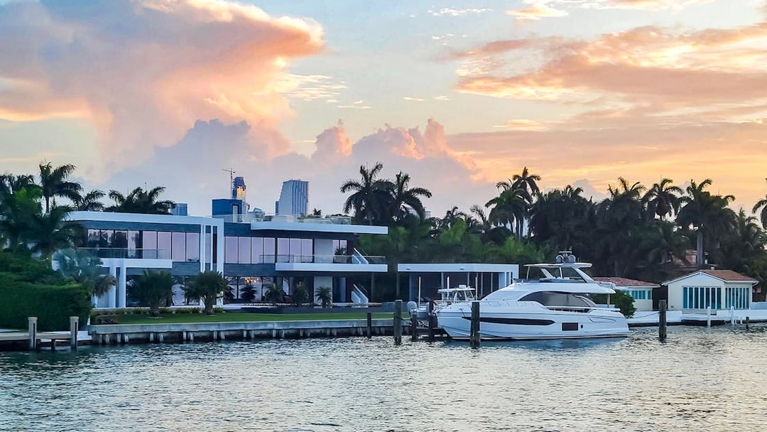 Luxury yacht docked at a waterfront mansion during sunset in Biscayne Bay, South Beach.