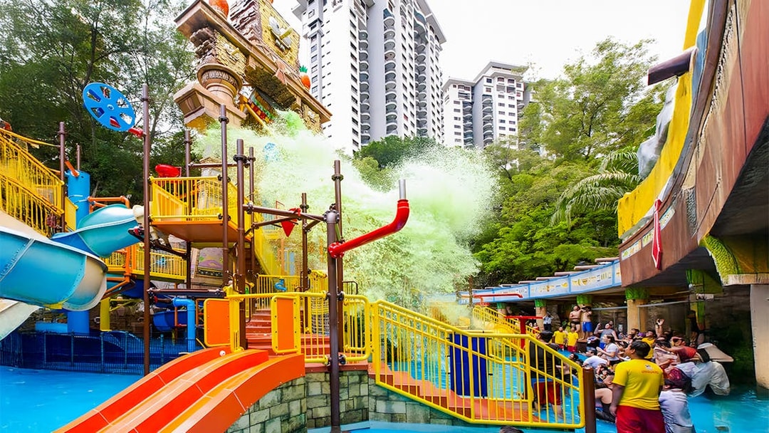 Sunway Lagoon water park splash area with slides and people enjoying the attractions.