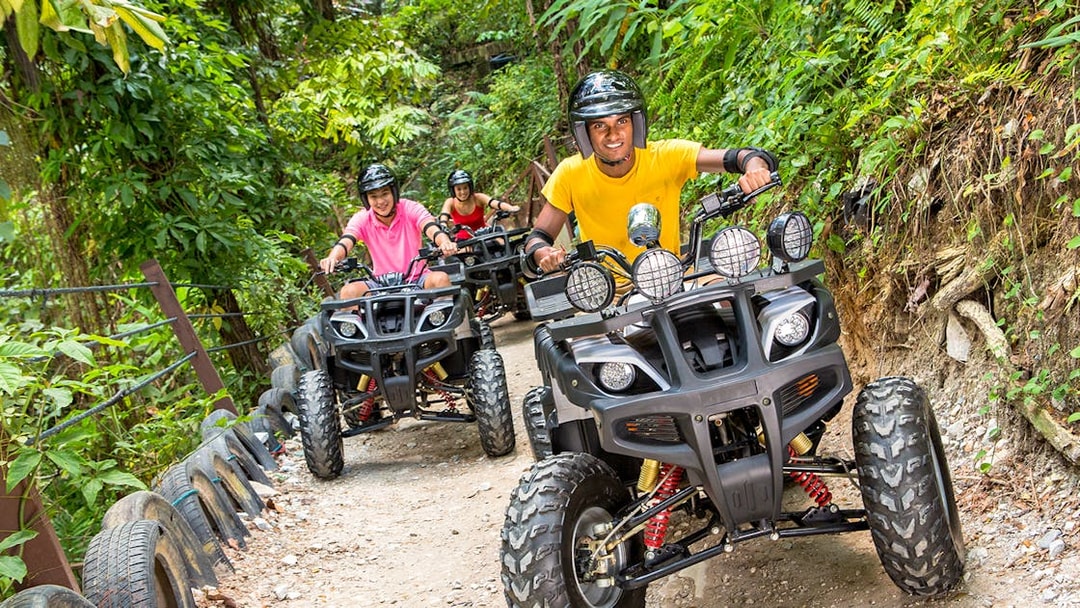 ATV riders on a forest trail at Sunway Lagoon theme park.