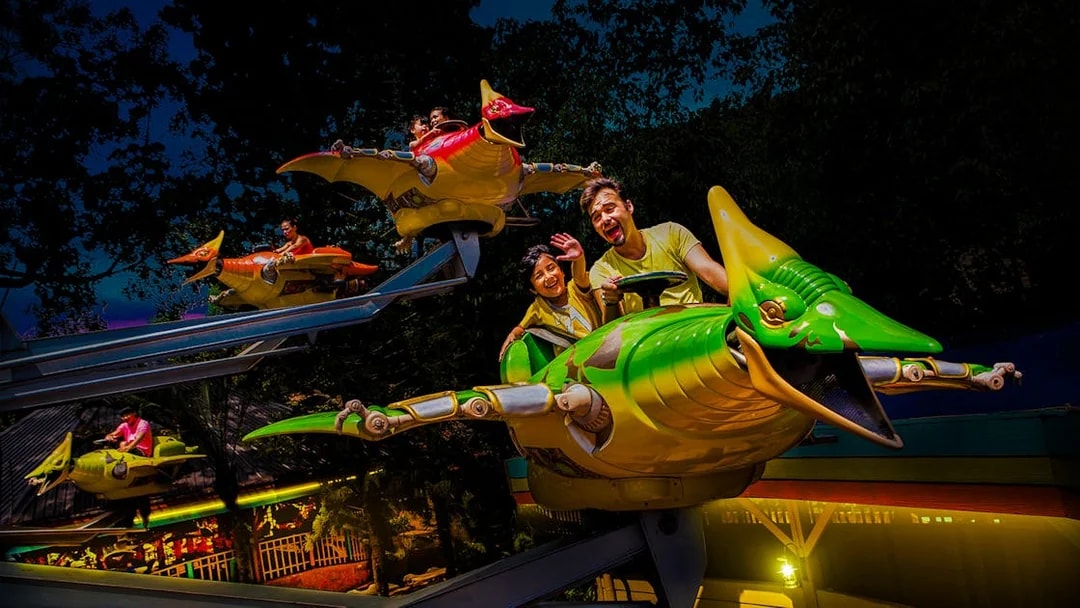 Riders enjoying a flying dinosaur ride at Sunway Lagoon night park.