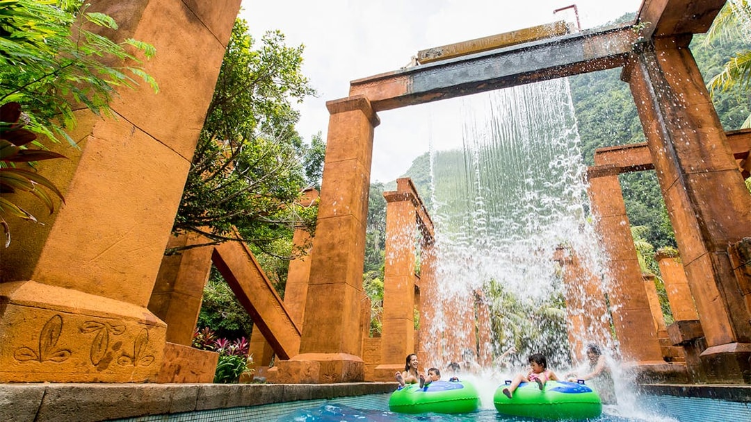 Visitors on water tubes under waterfall at Sunway Lost World of Tambun, Malaysia.