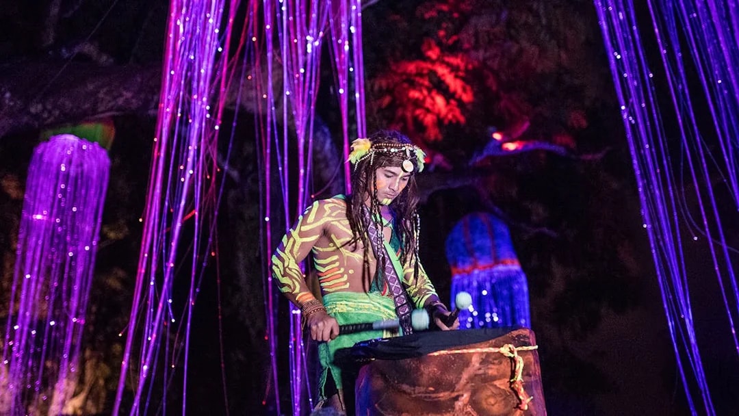 Performer in neon body paint playing drums at Sunway Lost World of Tambun, Malaysia.