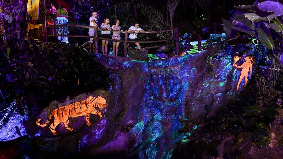 Visitors observing illuminated rock art at Sunway Lost World of Tambun, Malaysia.