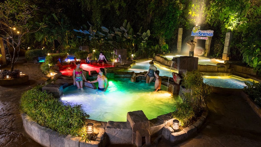Visitors enjoying hot springs at Sunway Lost World of Tambun, Malaysia, surrounded by lush greenery.
