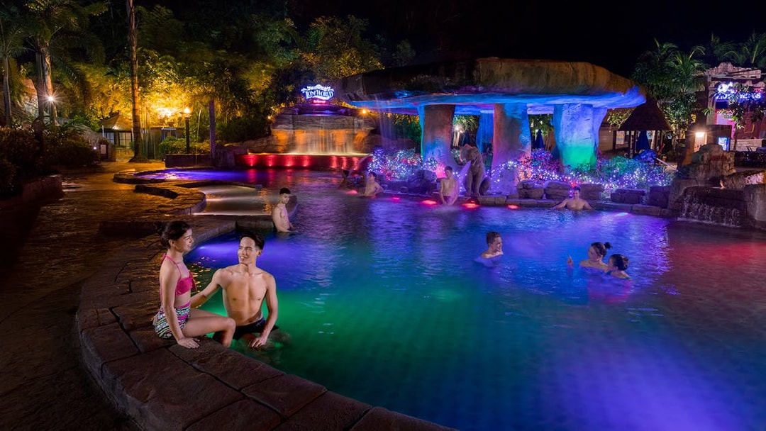 Visitors enjoying the illuminated hot springs at Sunway Lost World of Tambun at night.