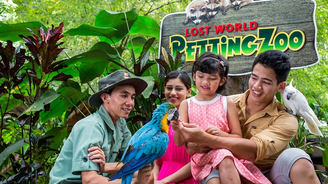 Family interacting with parrots at Lost World Petting Zoo, Sunway Lost World of Tambun, Malaysia.